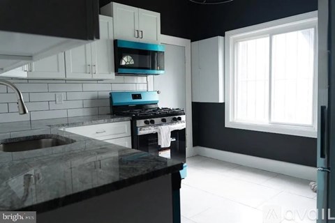 A kitchen with a black counter top and white cabinets.