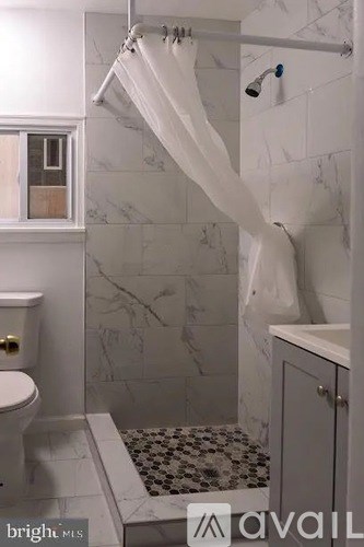 A bathroom with a toilet, a shower curtain, and a shower mat.