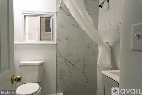 A bathroom with a toilet, sink, and shower.