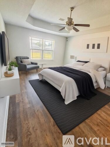 A bedroom with a bed, chair, and ceiling fan.