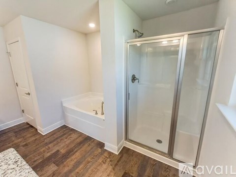 A bathroom with a glass shower door and a bathtub.