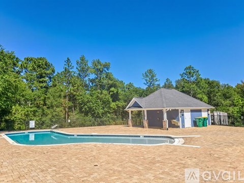 A swimming pool in a backyard with a pavilion and trees in the background.
