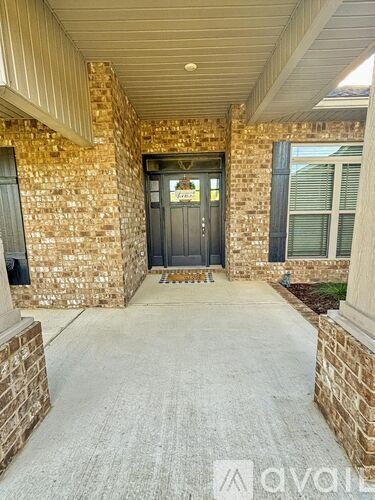 A front porch with a black door and a brick wall.