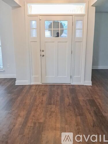 A white door with a glass window is in a room with wooden flooring.