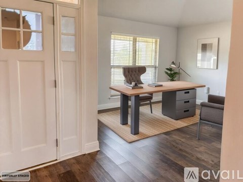 A room with a desk, chair, and a plant.