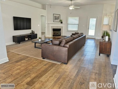 A living room with a brown leather couch and a fireplace.