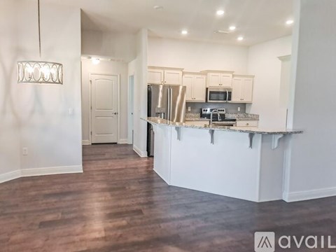 A kitchen with white cabinets and a wooden floor.