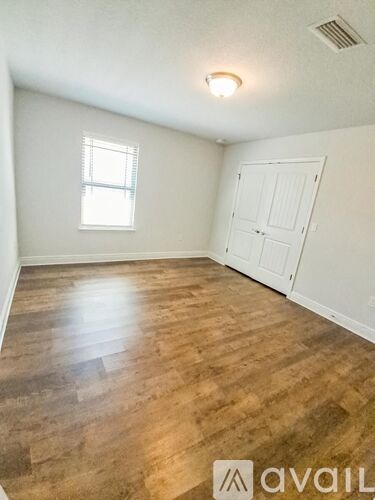 A room with wooden flooring and a white door.