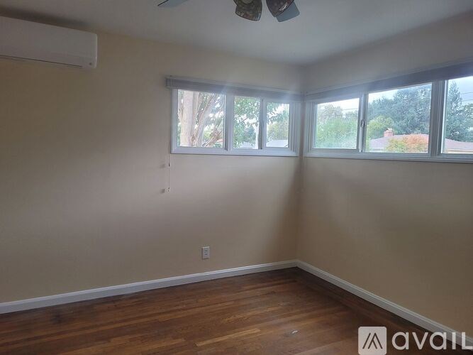 A room with a ceiling fan and large windows.