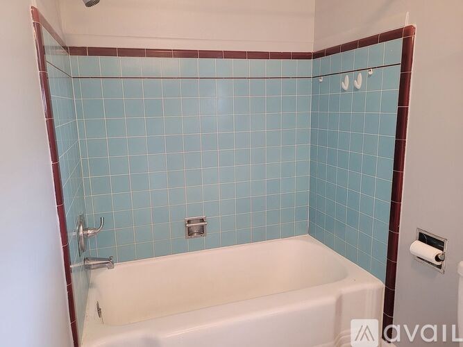 A white bathtub with a blue tiled wall.