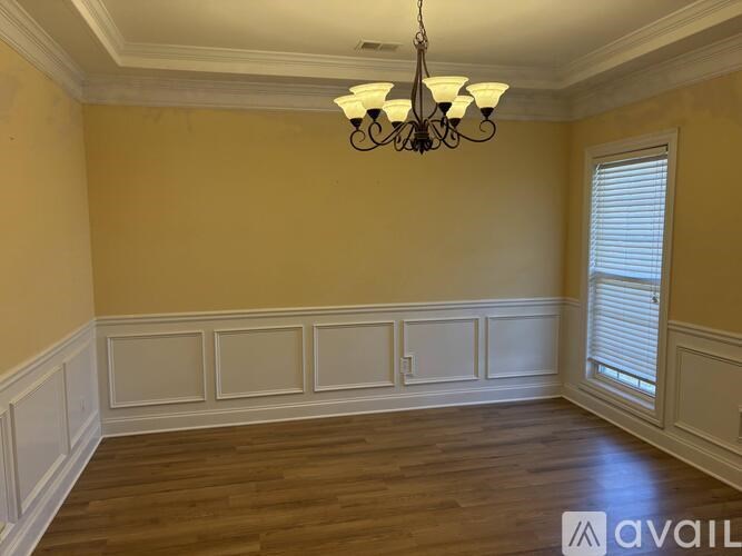 A room with a chandelier and wooden floors.