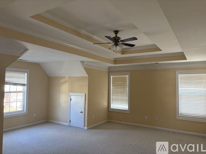 A room with a ceiling fan and two windows.