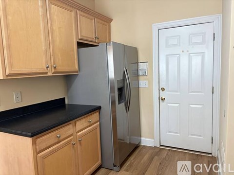 A kitchen with wooden cabinets and a stainless steel refrigerator.