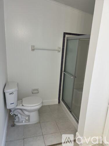 A white toilet with a tank and a toilet paper holder on the wall.