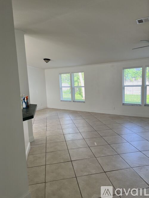 A large empty room with tiled flooring and two windows.