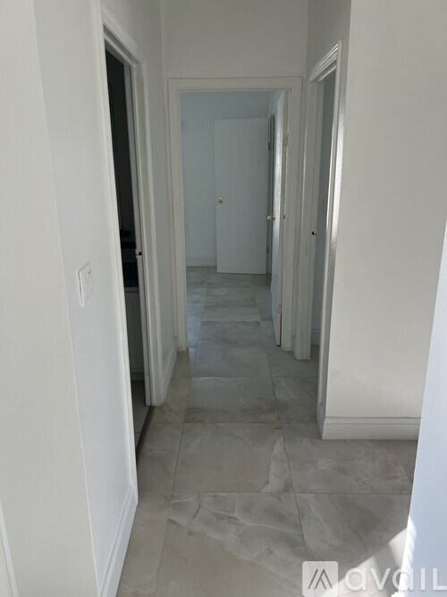 A long, narrow hallway with tiled floors and white walls.