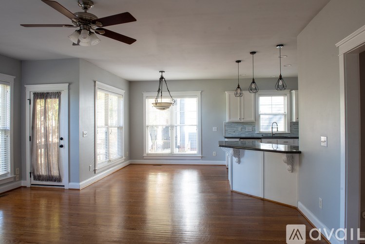 A spacious kitchen and living room with hardwood floors and a ceiling fan.
