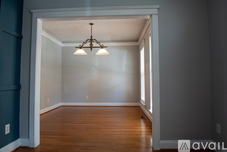 A room with a wooden floor and a chandelier hanging from the ceiling.