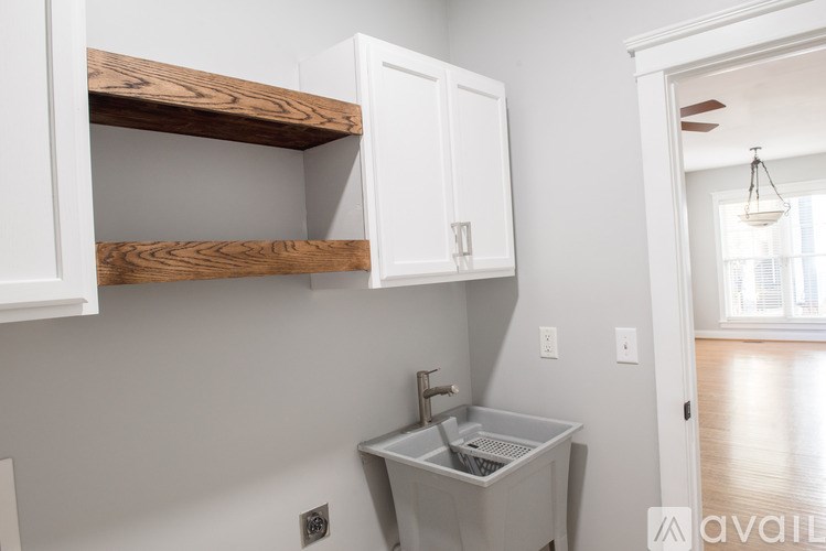 A kitchen with white cabinets and a wooden shelf above the sink.