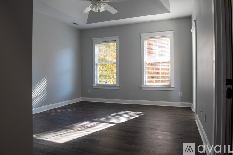A room with a ceiling fan and two windows.