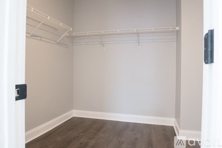 A walk-in closet with a white door and a wooden floor.