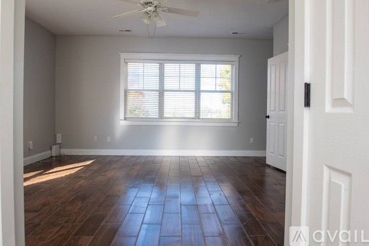 A room with a ceiling fan and a window with blinds.