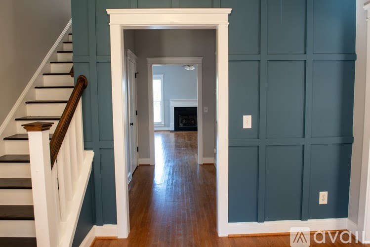 A hallway with a staircase on the left and a doorway leading to another room.
