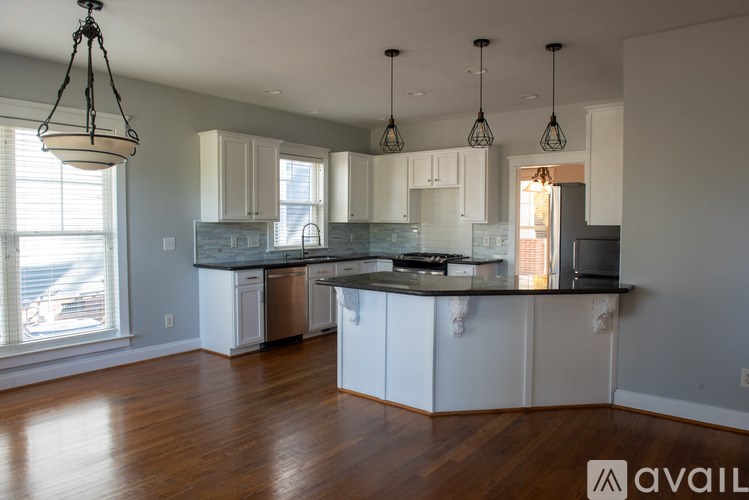A kitchen with white cabinets and a wooden floor.