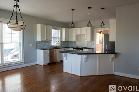 A kitchen with white cabinets and a wooden floor.