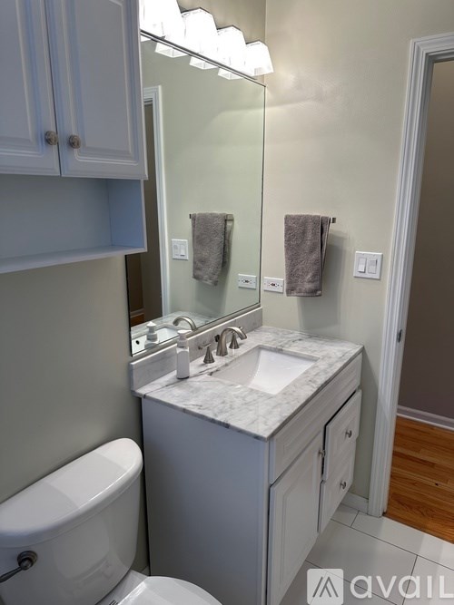 A bathroom with a toilet, sink, and mirror.