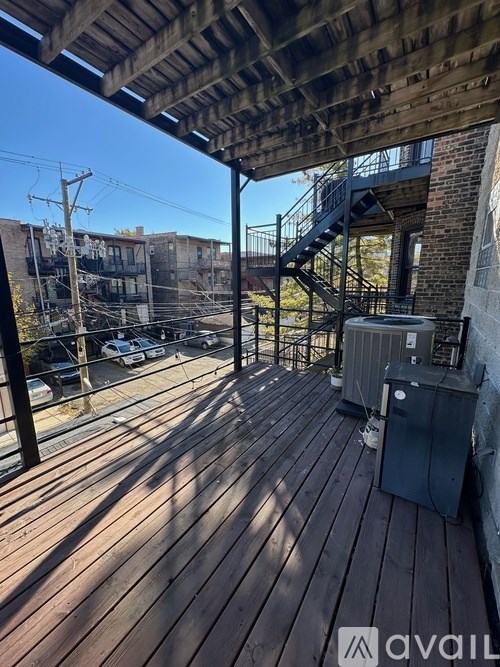 A wooden deck with a metal railing and a staircase leading to a balcony.