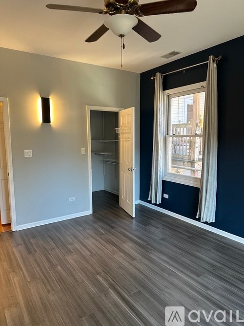 A room with a ceiling fan and a window with curtains.