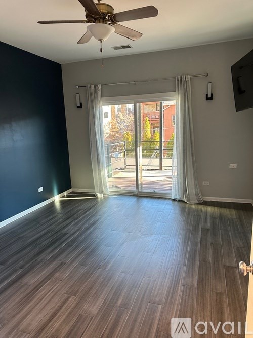 A room with a ceiling fan and sliding glass doors leading to a balcony.