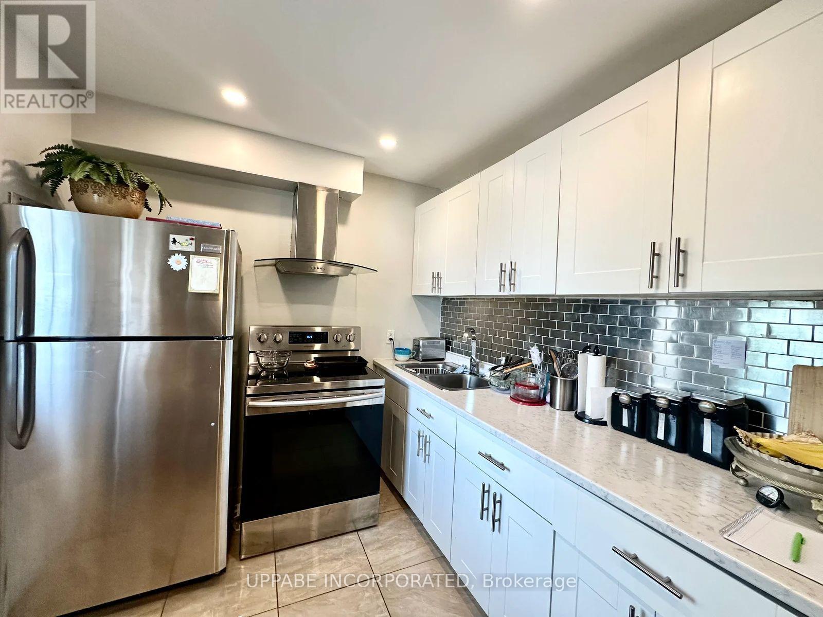 A kitchen with a stainless steel refrigerator and white cabinets.