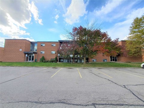 A parking lot in front of a brick building with trees.