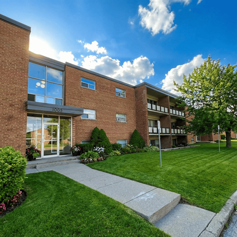 A modern brick building with a glass entrance and a well-maintained lawn in front.