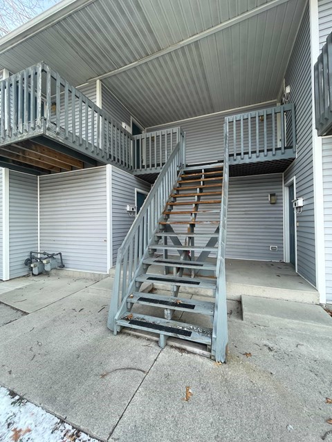 A grey metal staircase is in front of a grey building.