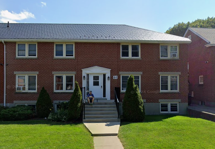 A red brick house with a white door and windows.