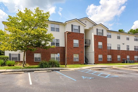 A parking lot in front of a two story apartment building.