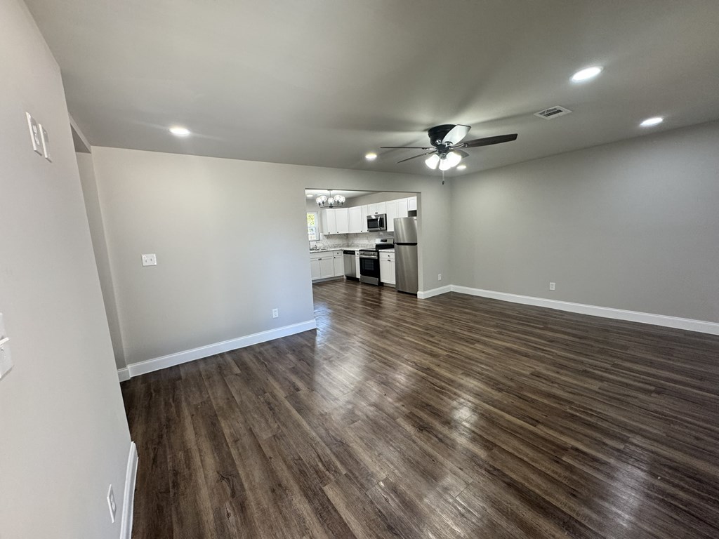 A room with a ceiling fan and wooden flooring.