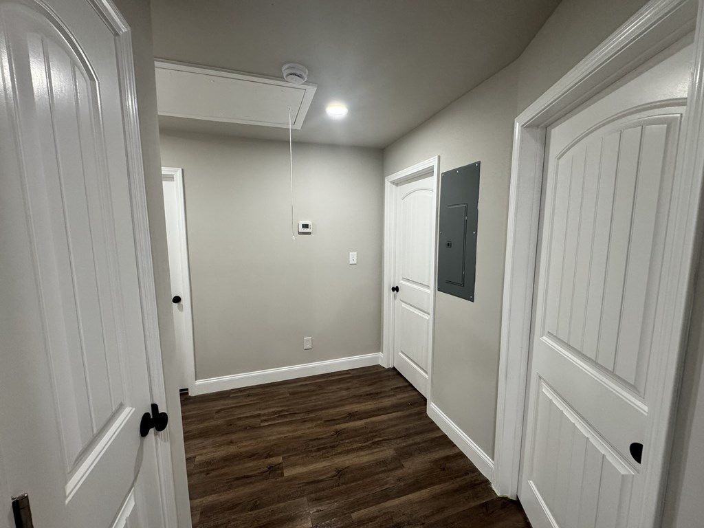 A hallway with wood floors and white walls.