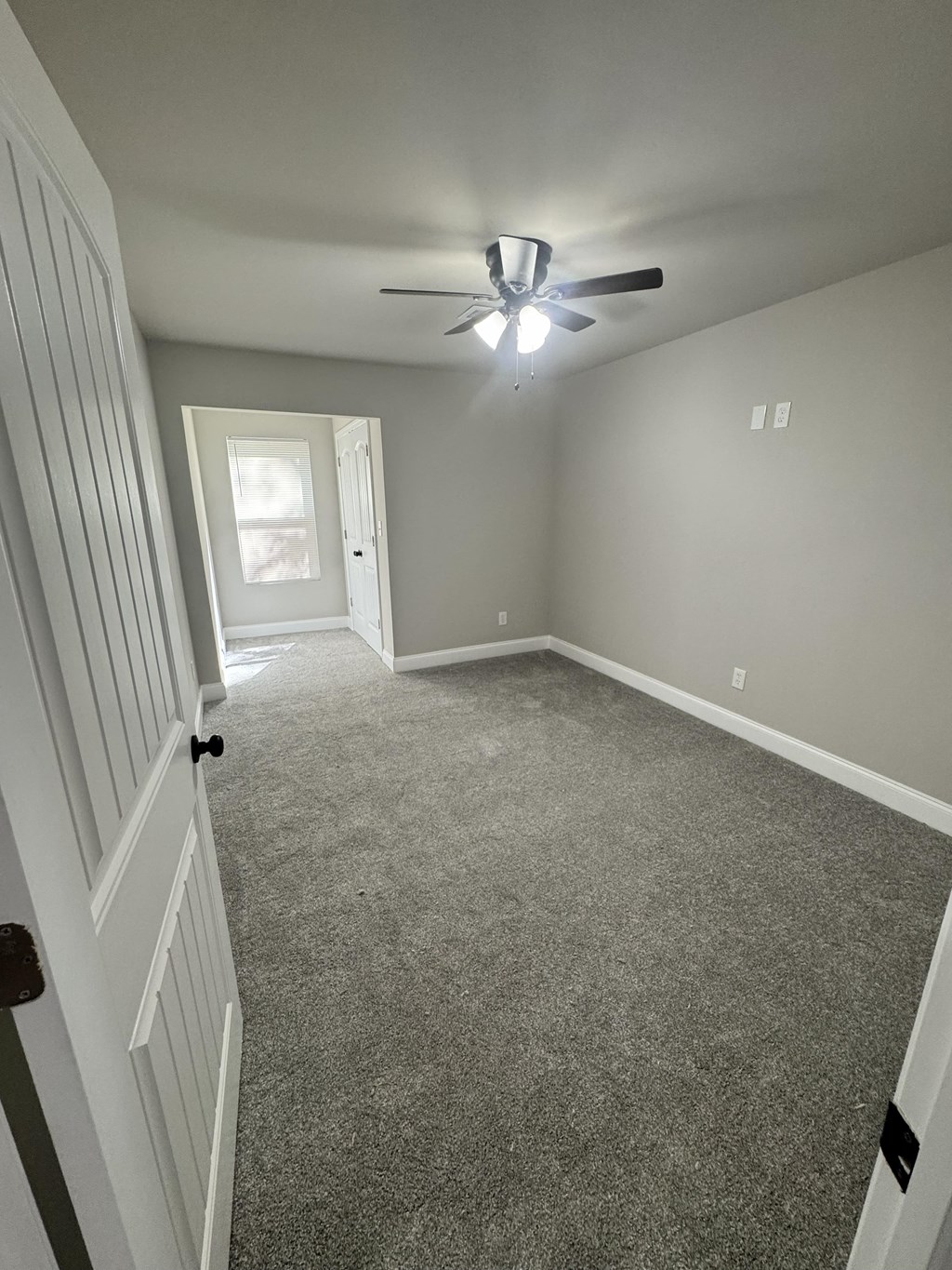 A room with a ceiling fan and carpeted floor.