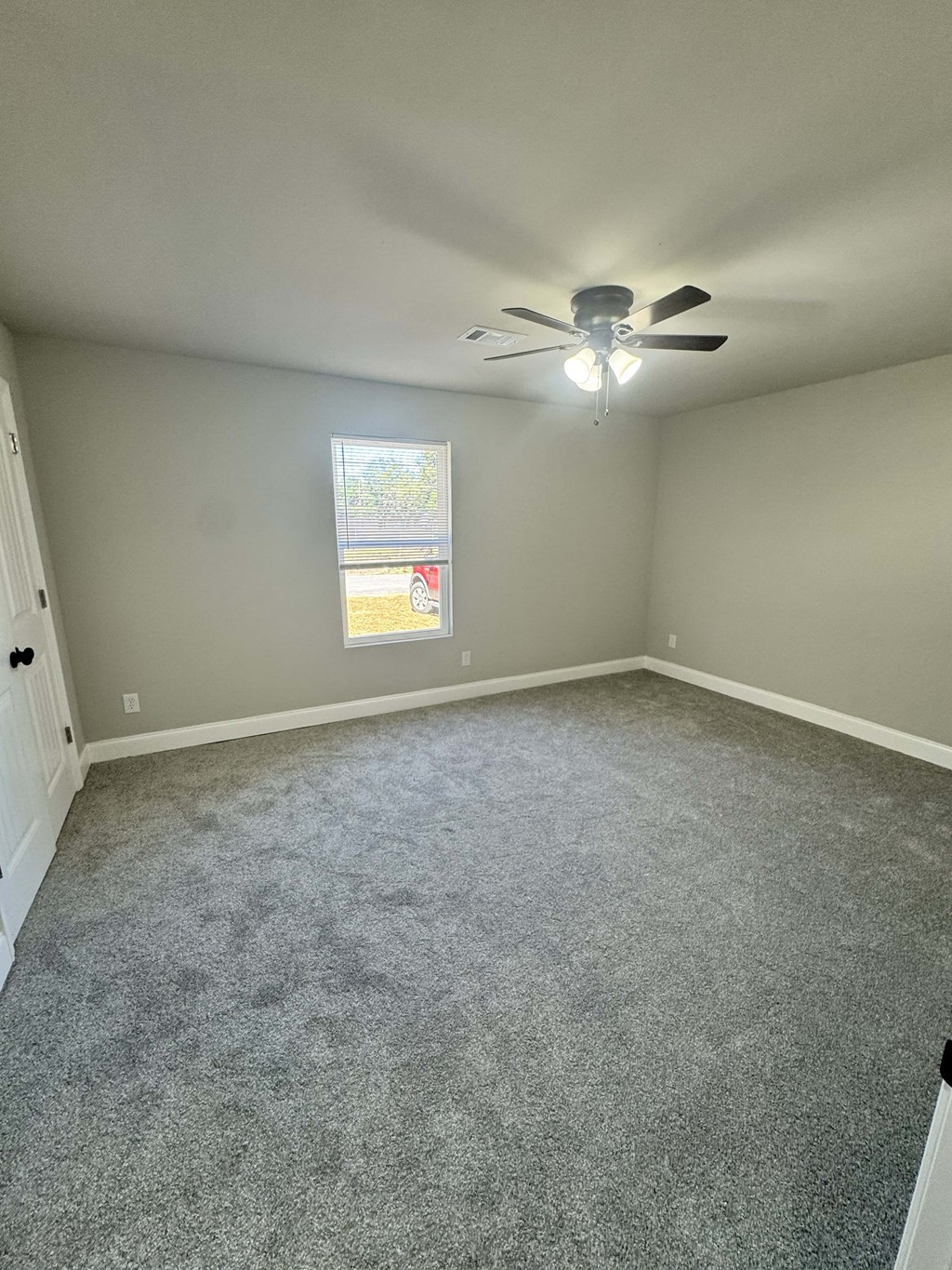A room with a ceiling fan and a window with blinds.