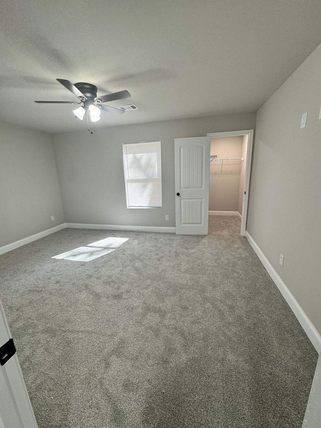 A room with a ceiling fan and carpeted floor.