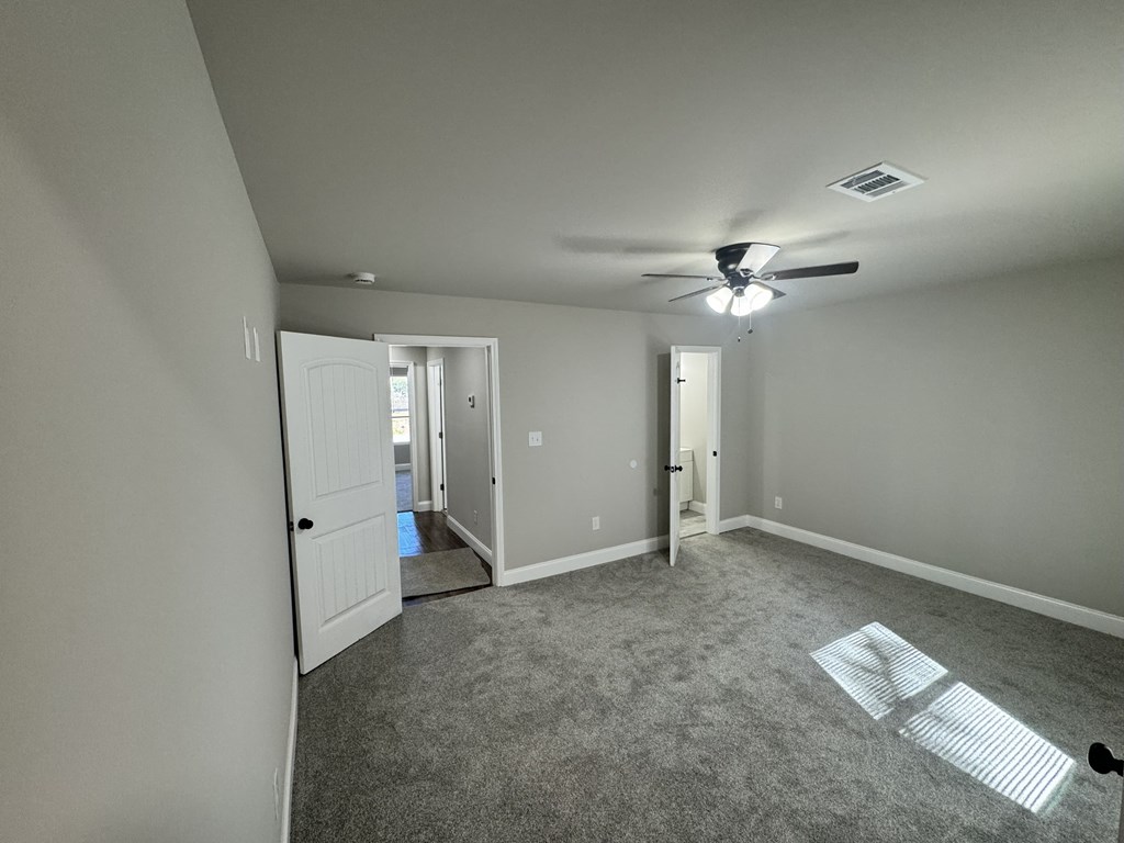 A room with a ceiling fan and carpeted floor.