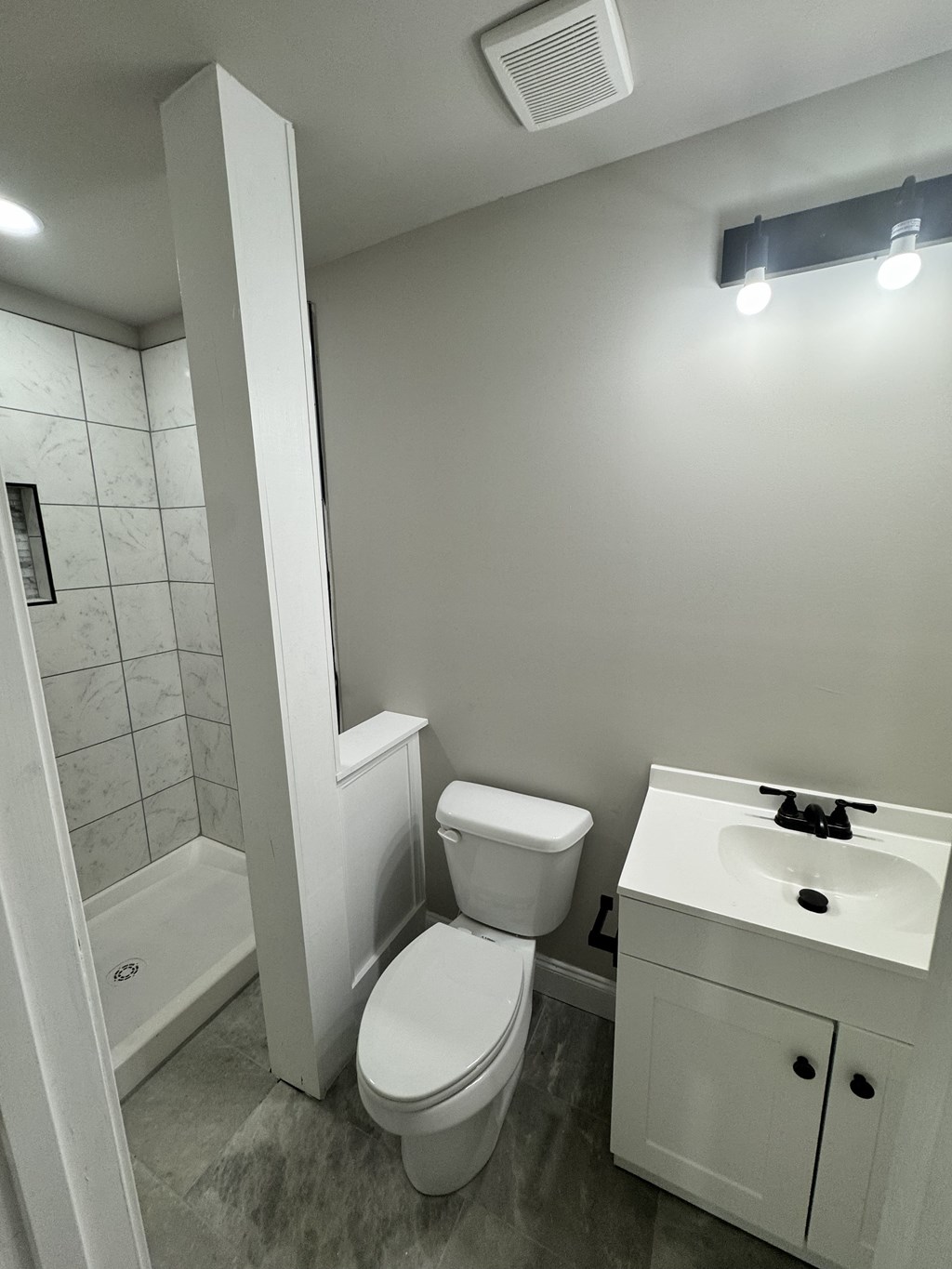 A white toilet sits next to a white sink in a small bathroom.