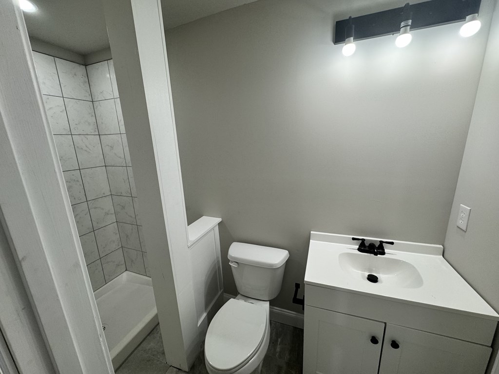 A white toilet sits next to a white sink in a small bathroom.