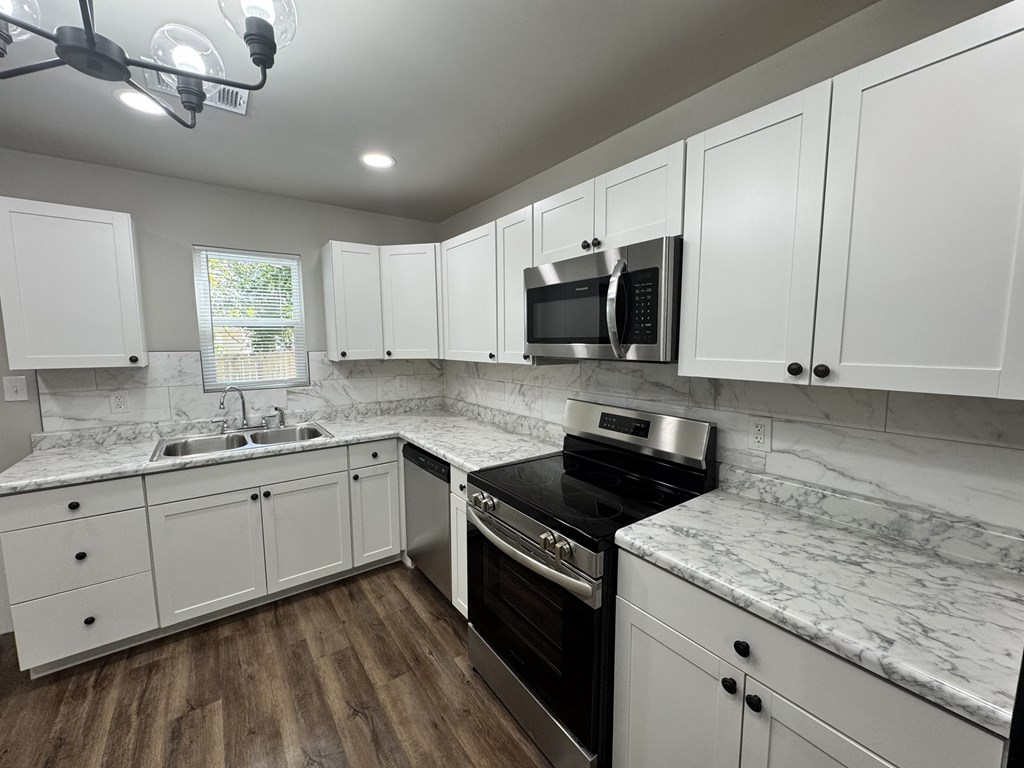 A kitchen with white cabinets and a black stove top oven.