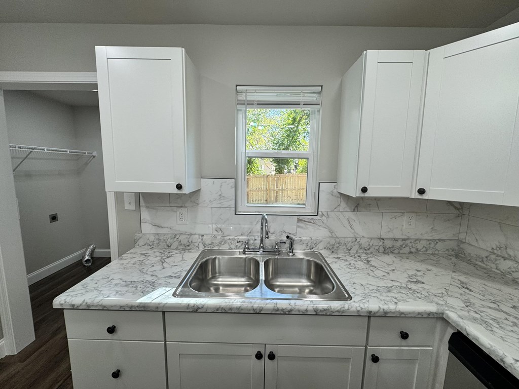A kitchen with a marble countertop and white cabinets.