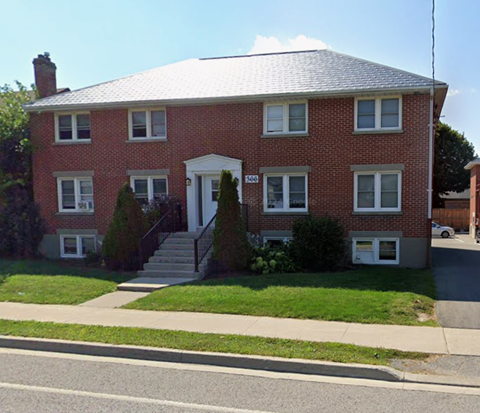 A red brick house with a white door and windows.